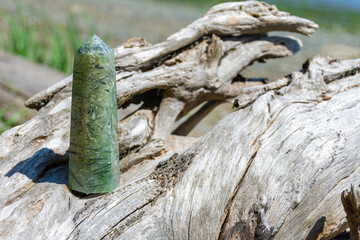 A close up image of a epidote crystal tower with tourmaline inclusions on a driftwood log. 