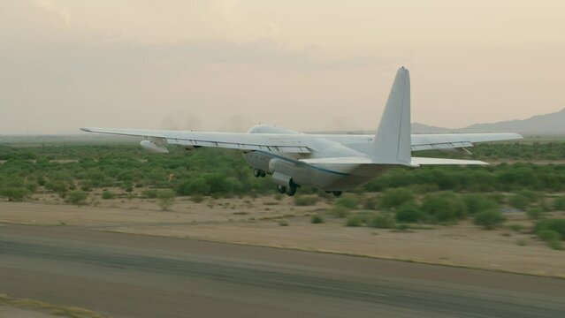 Cinematic shot of c-130 airplane taking off at dusk