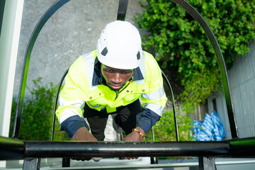 Technician climbs a ladder to the rooftop to check the installation of solar panels