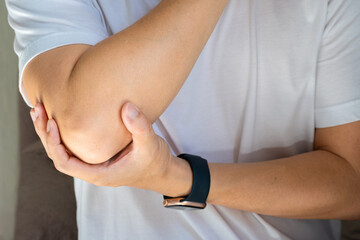 Naklejka premium Man has pain in his elbow and tendon muscles and he relieves the pain with a massage. Health and healing concept 
