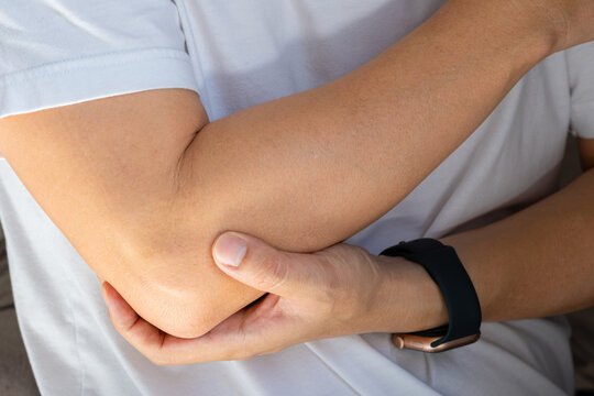 Man has pain in his elbow and tendon muscles and he relieves the pain with a massage. Health and healing concept	
