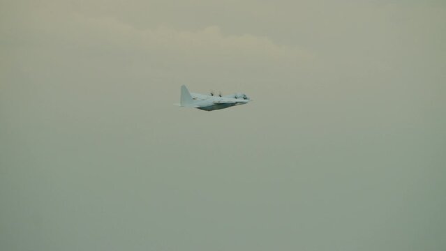 Zoom out on c-130 soaring through sky at dusk