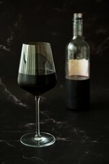 Glass of red wine and bottle on marble background