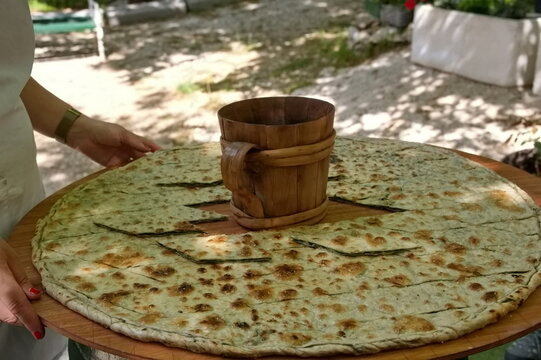 Soparnik - traditional Croatian food on big wooden plate with wooden mug in the middle