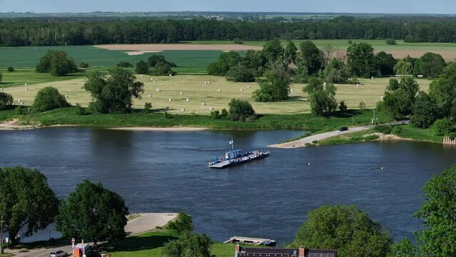 Ferry crosses the Elbe near Barby, Saxony-Anhalt. Flight from left to right. River in the center of the picture. Landscape with trees, meadows and fields on the other side of the river.