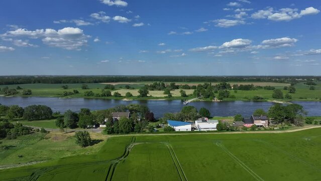 Elbe near Barby, Saxony-Anhalt. Flight from left to right. River in the center of the picture. Meadows and fields on both sides. Buildings in the foreground. Ferry dock in the center 