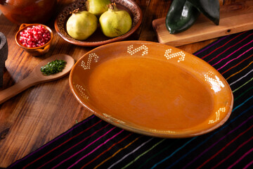 Mexican food background. Traditional empty clay plate on a rustic wooden table with basic...