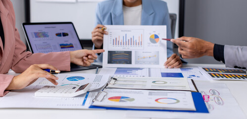 Group of confident business people point to graphs and charts to analyze market data, balance sheet, account, net profit to plan new sales strategies to increase production capacity. 