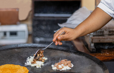 Obraz premium woman's hand cooking mexican food, heating tortillas and preparing carnitas y quesadillas