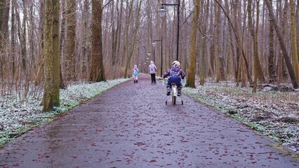 Happy Kids Riding Scooters and Learning to Ride Bike in City Park on Wet Cold Autumn Winter Day