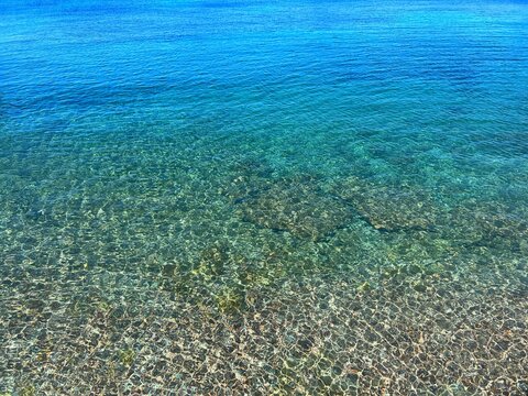 Blue sea clear calm water on pebble beach 