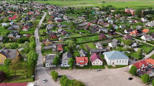 Establishing drone shot of small village in Lithuania surrounded by green fields, Sveksna