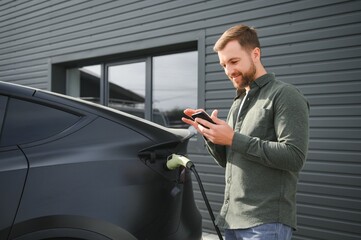 Man charging electric car by the house