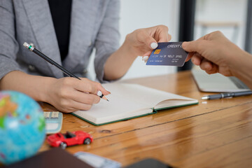 Female tourist pays by credit card to travel agent at office, travel concept