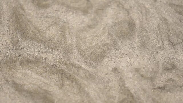 Sand particles flowing in crystal clear ocean water, close up view