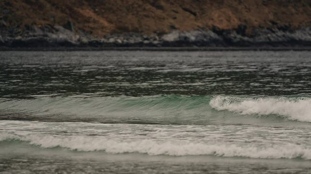 Ocean waves reaching sandy beach in Norway, follow view