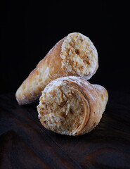Tube cake with white cream on a dark background. Two puff pastry cakes on a wooden board.