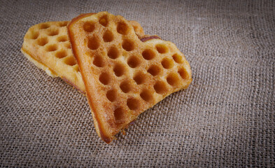 Two heart-shaped Viennese waffles lie on a jute napkin.