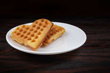 Two Viennese waffles lie on a white plate. Viennese waffles in the shape of a heart.