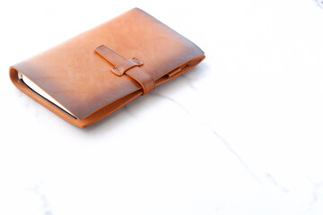 茶色の革のシステム手帳でデスクワークをしているイメージ
