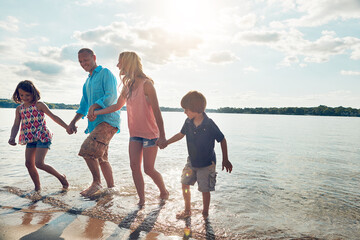 Family, playful and walking in beach or holding hands and travel for summer, holiday and nature of...