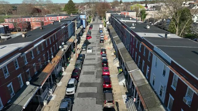 Dense populated street in american suburbia. Sunny Spring day in poor district of american town. Dense Parking cars in row. Dangerous borough in metropolis. Aerial top down flyover.