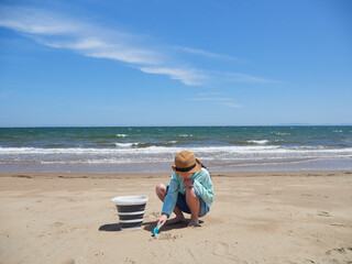 夏の海の海岸のビーチで砂遊びする一人の小学生の女の子の様子