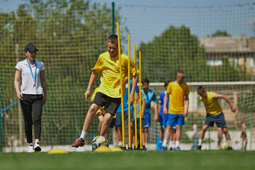 Outdoor Sports Training. Young soccer players, boys in uniforms in motion, training with special equipment. Outdoor activity with coach. Concept of sport, school, childhood, hobby, active lifestyle