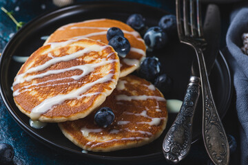 Pancakes with blueberries and condensed milk on a plate