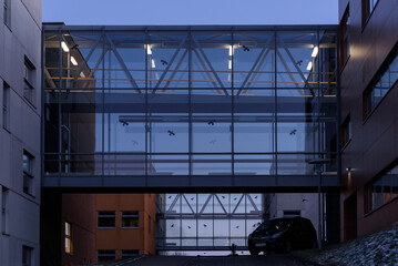 ARCHITECTURE - Modern buildings connected by a glass and steel bridge with preventive bird pictograms on transparent walls

