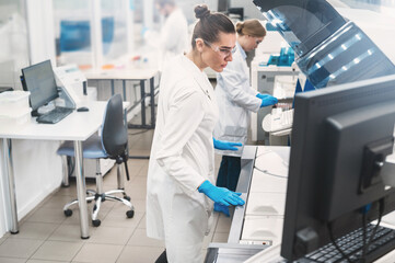 female doctor working in a modern equipped computer laboratory analyzes blood samples and genetic...