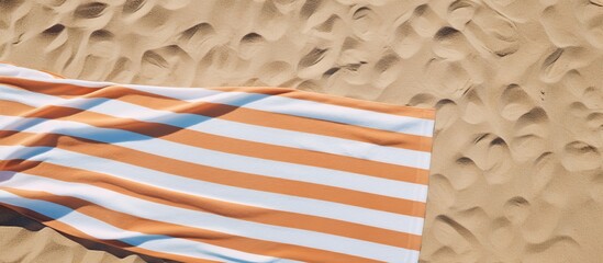 An aerial view of a beach towel with stripes on the sand provides a vibrant copy space image