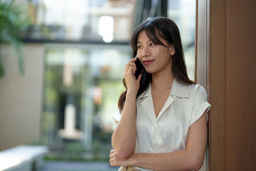 Fototapeta premium Modern smiling woman uses her phone to play online. Check finances via online banking Talk through the application Online communication, business ideas, learning.