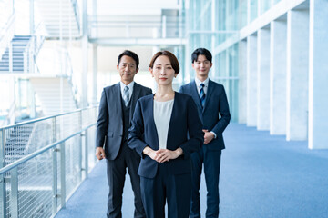 Fototapeta premium オフィスに立つスーツを着た3人