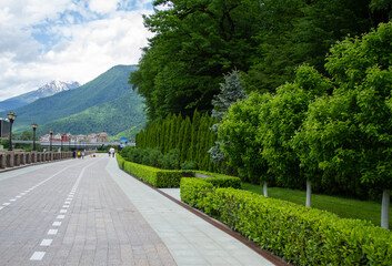 Fototapeta premium Rosa Khutor embankment, mountains and green forest. Krasnaya Polyana, Sochi.