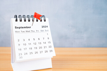 September 2024 calendar and red push pin on the table.