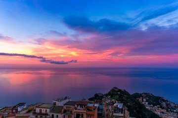 sceniv view from a high mountain town to amazing landscape of sea coast, roofs in vintage style of Italy and beautiful colorful sunset or sunrise cloudy sky