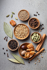 A variety of whole Indian spices in wooden bowls on a gray background top view vertical