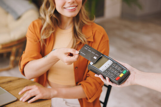 Cropped woman hold bank payment terminal to process acquire credit card pay bill sitting alone at table in coffee shop cafe relax rest at restaurant indoor. Freelance mobile office business concept.