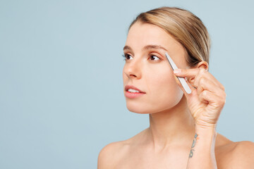 Close up side view beautiful half naked topless young woman with nude make up plucking out hair...