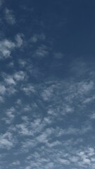 A serene image showcasing a clear blue sky dotted with wispy, white clouds.