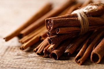 Cinnamon sticks dried tree bark spice on rustic wooden table background. Selective focus.