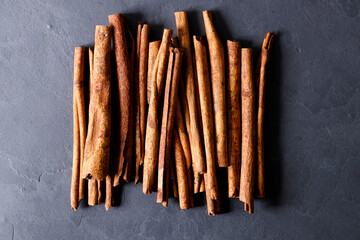 Cinnamon sticks dried tree bark spice on black stone table background. Selective focus.