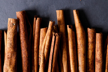 Cinnamon sticks dried tree bark spice on black stone table background. Selective focus.