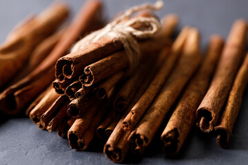 Cinnamon sticks dried tree bark spice on black stone table background. Selective focus.
