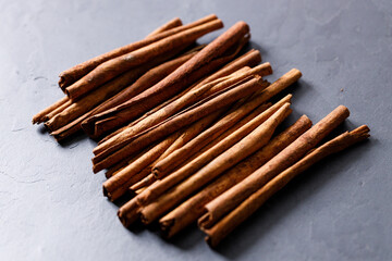 Cinnamon sticks dried tree bark spice on black stone table background. Selective focus.