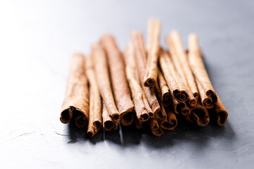 Cinnamon sticks dried tree bark spice on black stone table background. Selective focus.