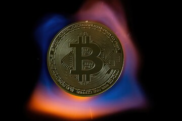 A bitcoin coin in the tongues of a hot flame. Real photo