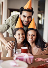 Parents, kid and home in portrait for birthday celebration in table with party hat and fun. People, family and smile or happy with love, care and support or bonding in special event and present
