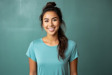 Fototapeta premium Portrait of a cheerful woman in her 20s wearing a moisture-wicking running shirt while standing against minimalist or empty room background